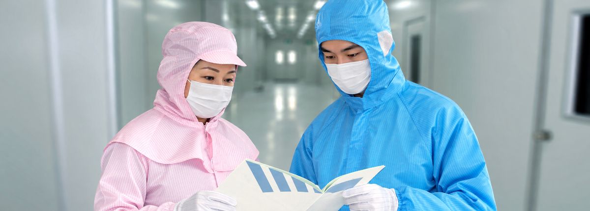 洁净车间内两名身穿洁净服的人员查看文件